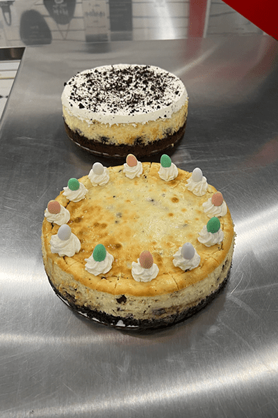 Two cakes on a metal surface with frosting and candies.