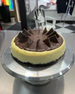 A chocolate and vanilla cheesecake on a cake plate.