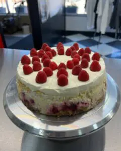 A cake with raspberries on top of it.
